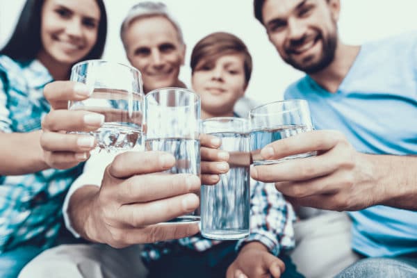 Smiling Family Drinking Water in Glasses at Home scaled
